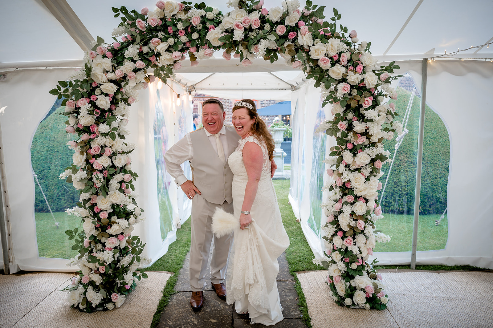bride and groom enter their marquee through a floral arch